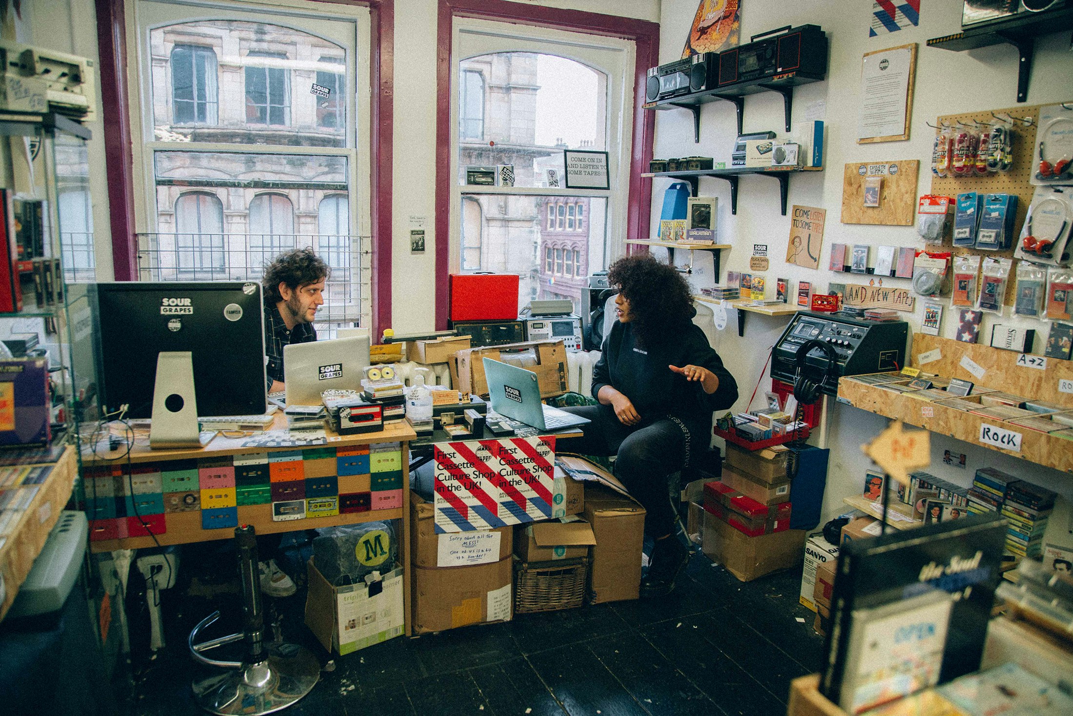 The author, Amelia Fearon (at right), speaks to Sour Grapes Records cofounder Giorgio Carbone at his retail store, Mars Tapes, in Manchester. Photo by Diogo Lopes.